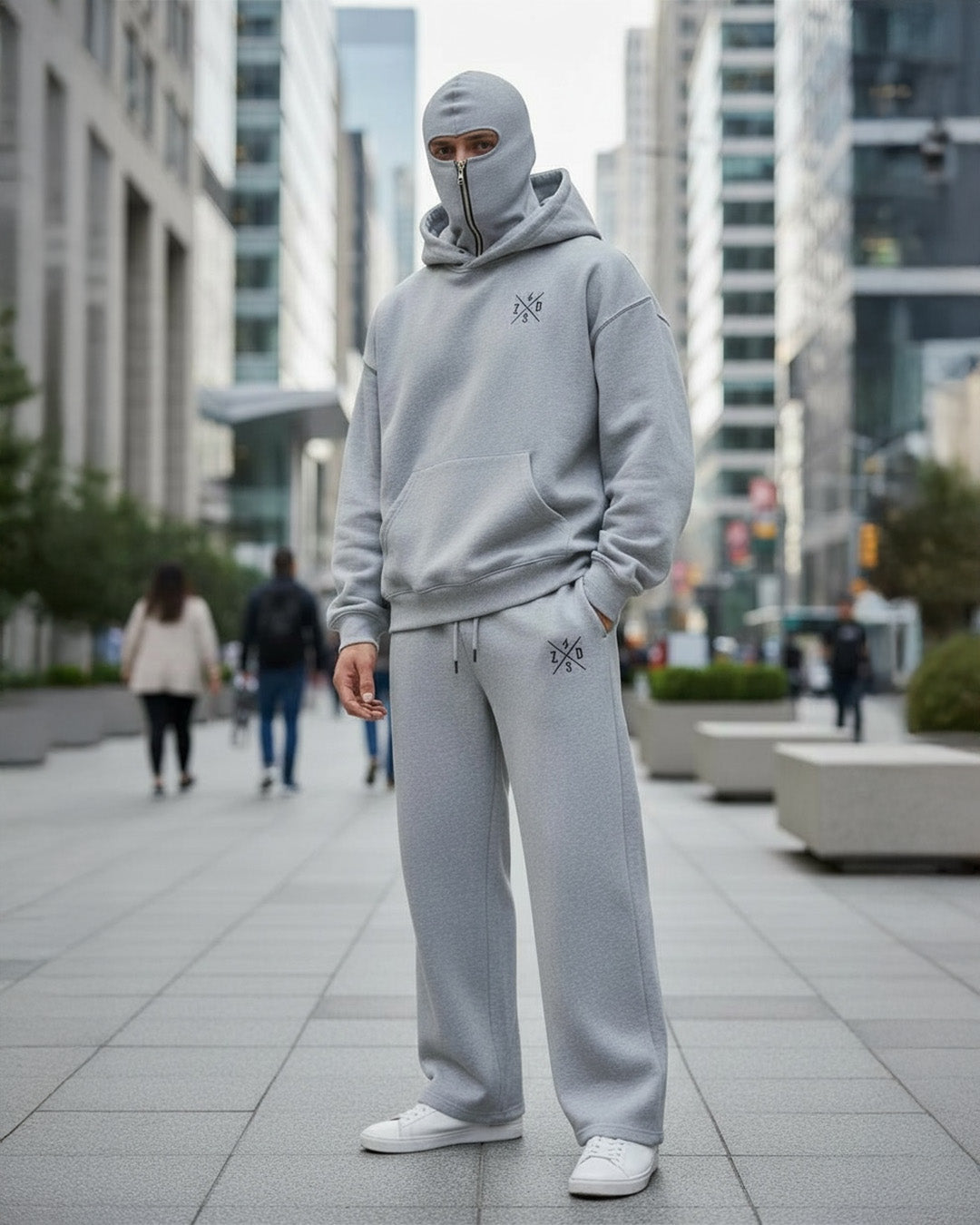 a men stand on a dubai street and looking front in camera and wear ninja hoodie co-ord set with attach mask and white shoes.