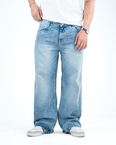 Man wearing light wash baggy wide-leg jeans with a white t-shirt and white sneakers, showing a relaxed 90s-inspired denim style